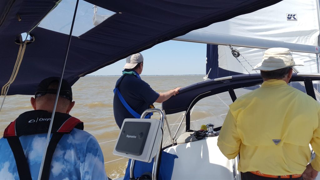 Image of the crew riding on the sailboat on the water