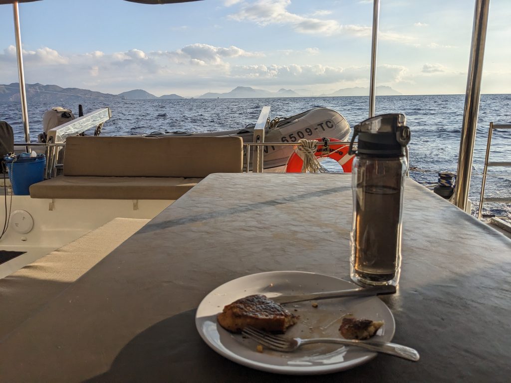 Image of a plate of french toast and a water bottle, which are resting on a table on a boat at sea.