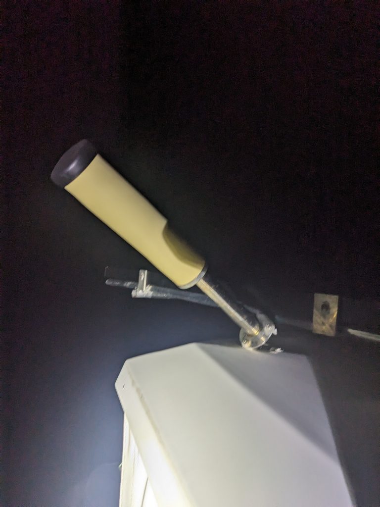 Image of an antenna coming off of its support mounts, taken at night
