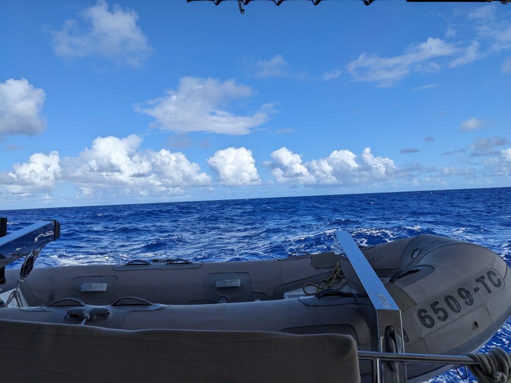 Image of the sea during the day with blue skies, taken from the back of a boat