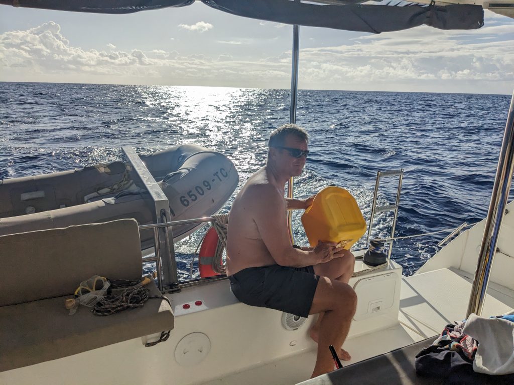 Image of man filling up a sailboat's fuel tank using a plastic gas can