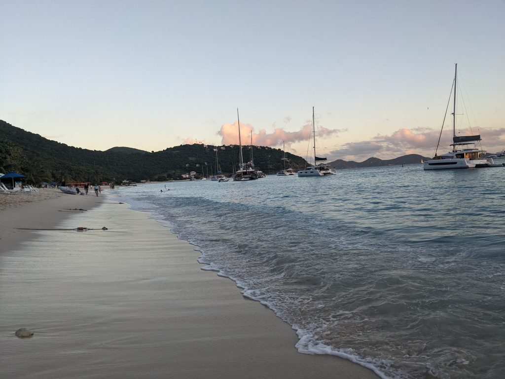 Image of a sandy coastline with sailboats moored in the background
