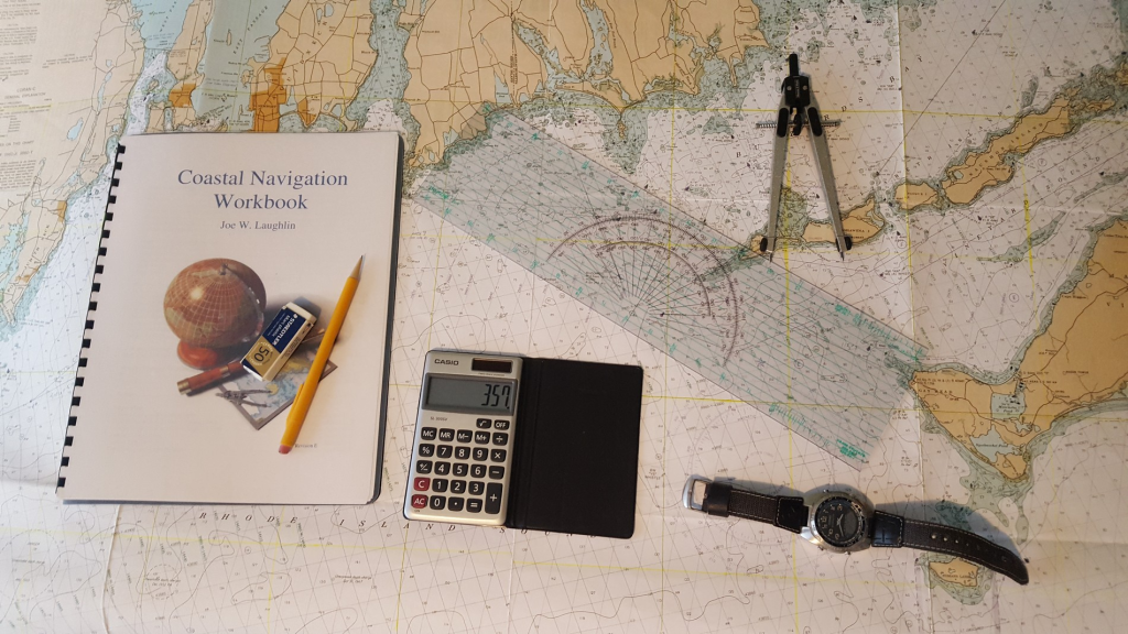 Image of a nautical chart with notebook. pencil, eraser, calculator, wristwatch, overlay plotter, and dividers on top