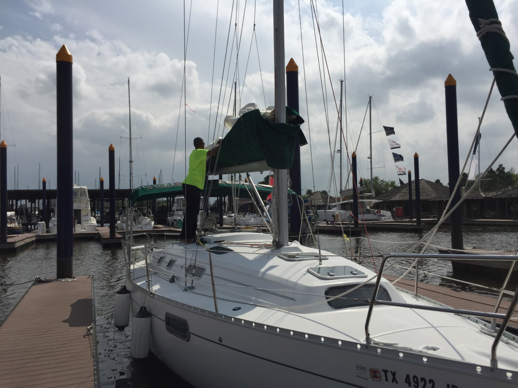 Image of a sailboat docked in its slip with a man tending to the sails