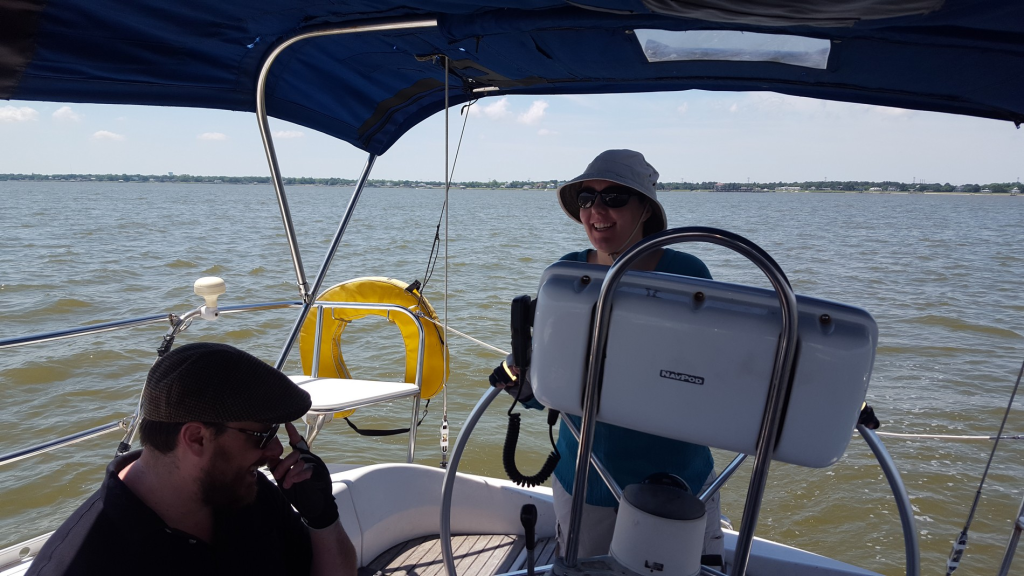 Image of smiling woman at the helm of a boat at sea