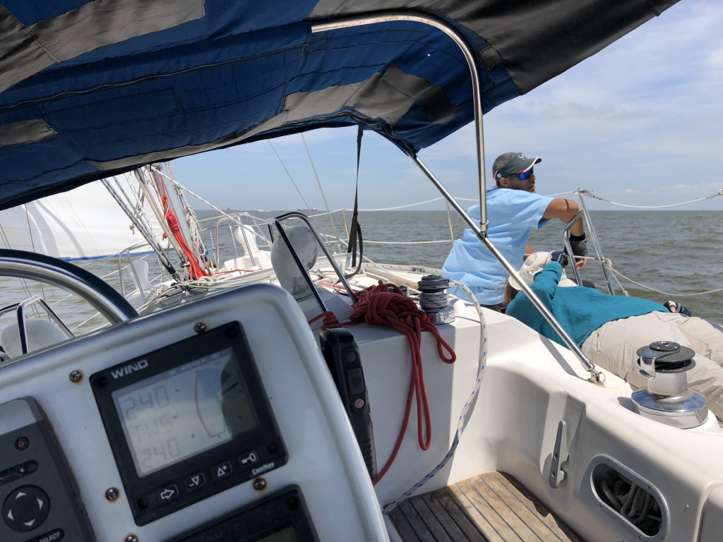 Image of two crew members lazing around a sailboat - one looking out and the other lying down flat on her back
