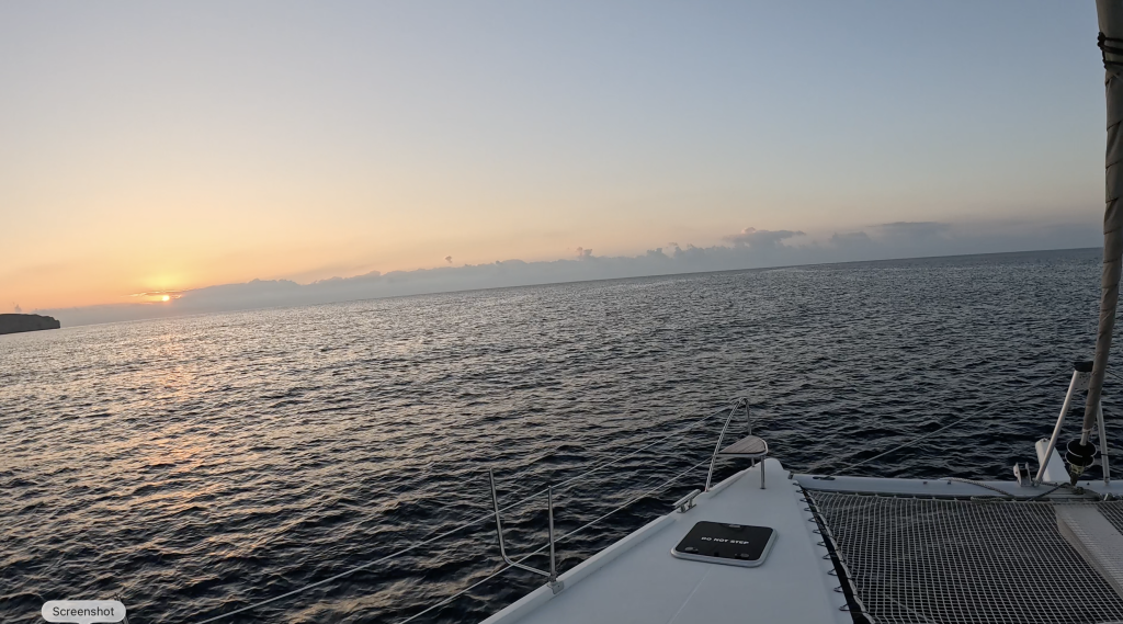 Image of the sea at sunrise, taken from the bow of a catamaran.